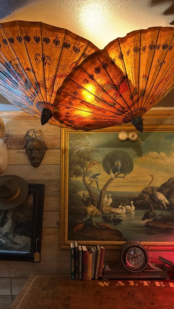 A glowing antique fan and a wall of collected artwork inside The Shack