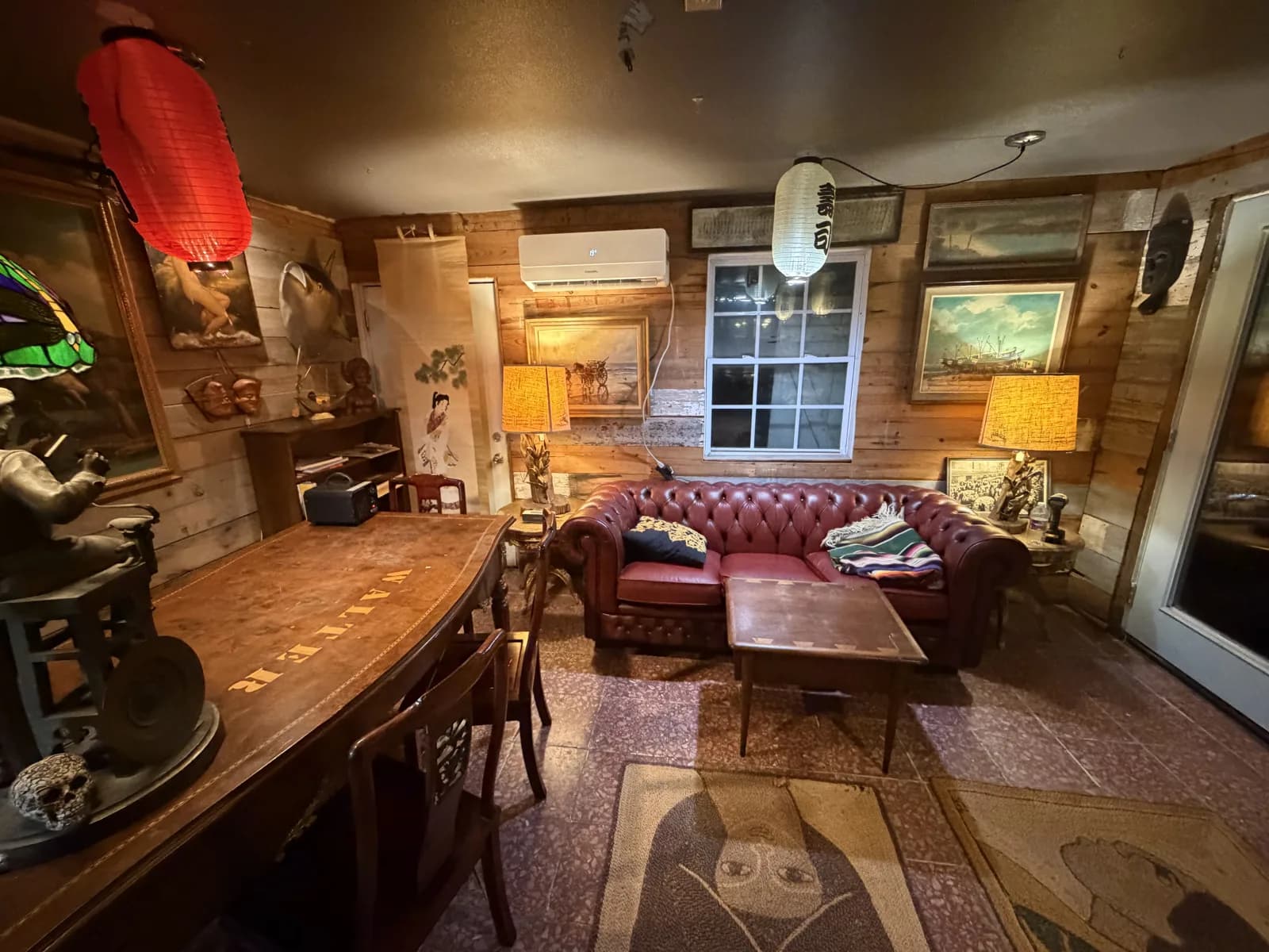Warm lamplight, antique artwork and a burgundy leather sofa inside The Shack